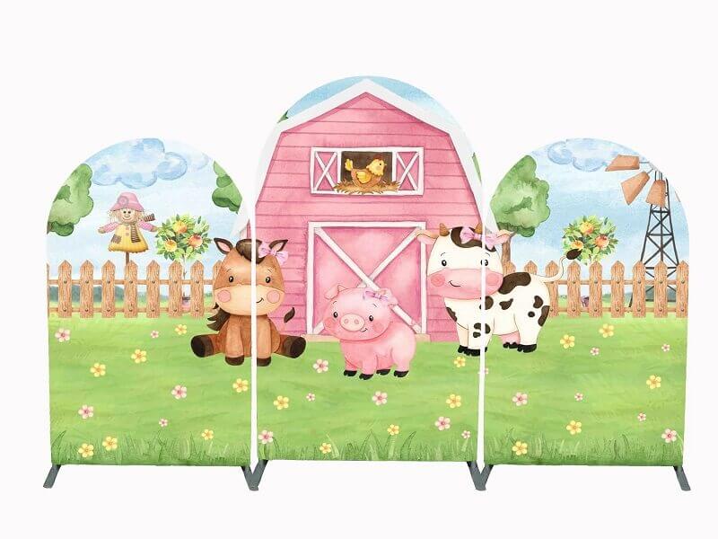 Farm-themed three-panel arch backdrop featuring a pink barn, a scarecrow, a windmill, and farm animals including a cow, pig, horse, and chicken in a flowery green field.
