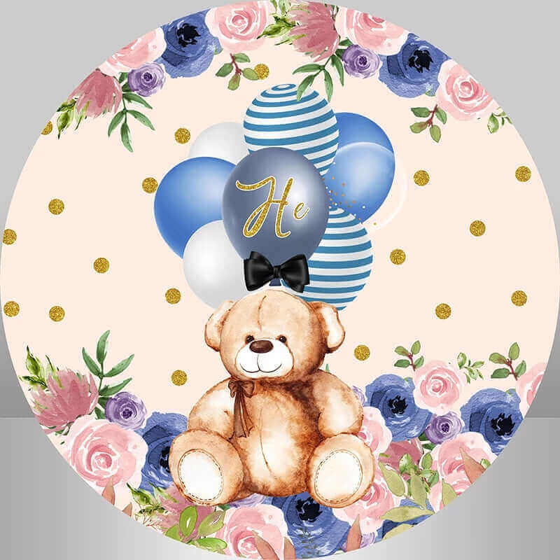 Teddy bear round backdrop with blue and white balloons, floral accents, and a 'He' balloon, set against a peach background with golden polka dots for a boy gender reveal.