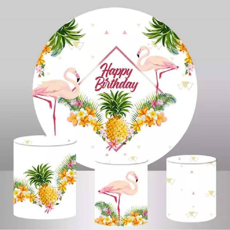 Tropical flamingo and pineapple birthday round backdrop with vibrant tropical flowers, leaves, and a 'Happy Birthday' message, complemented by three matching cylinder covers with pineapples, flamingos, and geometric patterns.