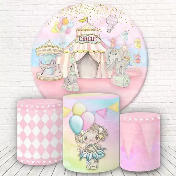 A round circus-themed pink backdrop featuring a circus tent, elephants, a carousel, balloons, and a Ferris wheel, paired with cylinder covers decorated with pink diamonds, a circus girl, and pastel tones with stars.