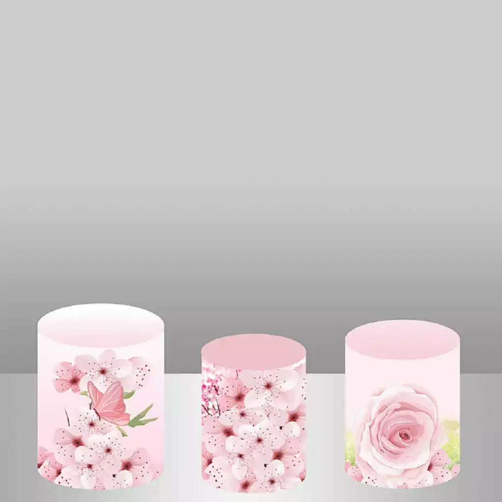 A set of three cylinder covers featuring pink cherry blossoms with a butterfly, clustered floral designs, and a single large pink rose for a cohesive, floral-themed decor.