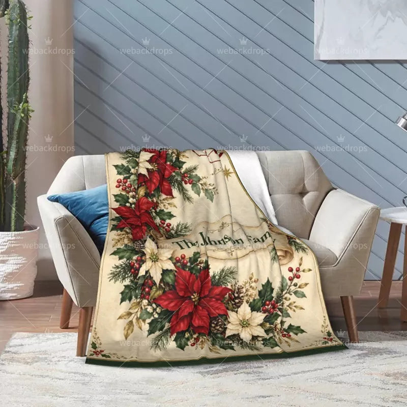 Personalized poinsettia Christmas blanket draped over a light-colored armchair, showing festive floral artwork and a soft white reverse side.