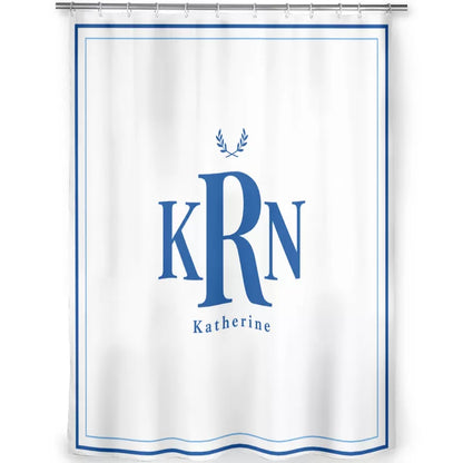 Front view of a white shower curtain featuring blue KRN initials, the name Katherine, a laurel wreath motif, and a double-line blue border with a wavy bottom edge.