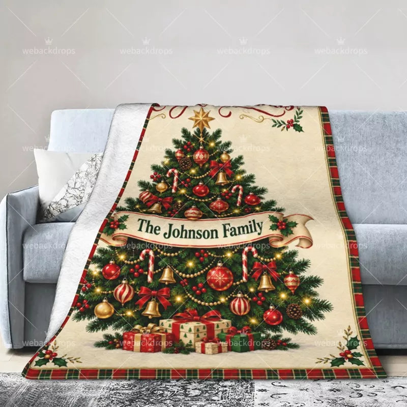 Personalized family Christmas throw blanket draped over a sofa, featuring a festive tree, ornaments and custom name.