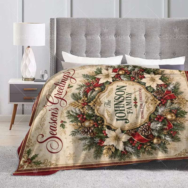 Custom family name Christmas throw blanket draped over a light-colored sofa, featuring an ornate gold crest and traditional holiday wreath.
