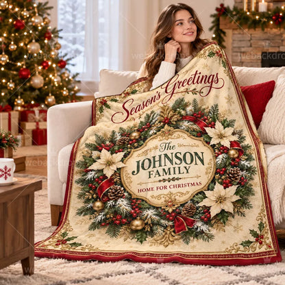 Woman wrapped in a personalized Christmas wreath blanket featuring vintage gold details and the Johnson family name beside a Christmas tree.