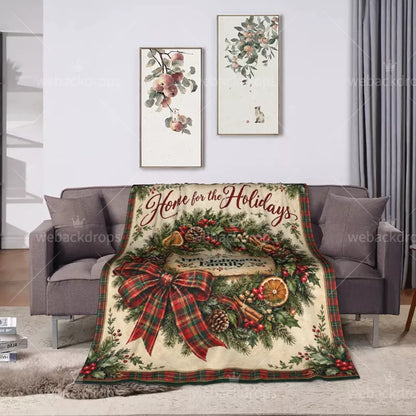 Farmhouse plaid Christmas throw blanket displayed on a gray living room sofa with a festive evergreen wreath and personalized family name design.