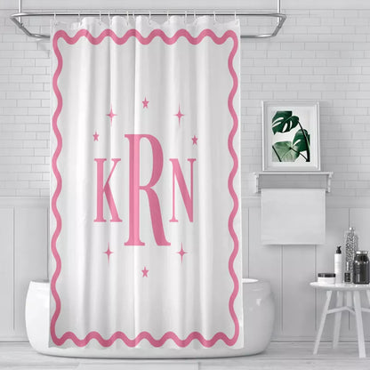 White shower curtain with a pink wavy border, large KRN monogram, and decorative pink stars displayed in a modern bathroom.