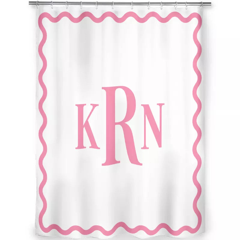 Front view of a white shower curtain featuring a pink wavy border and large KRN monogram, hanging from a silver shower rod.